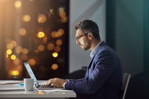 Shot of a businessman using a laptop while woking late at the office